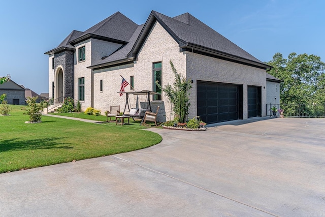 french provincial home with a front lawn and a garage