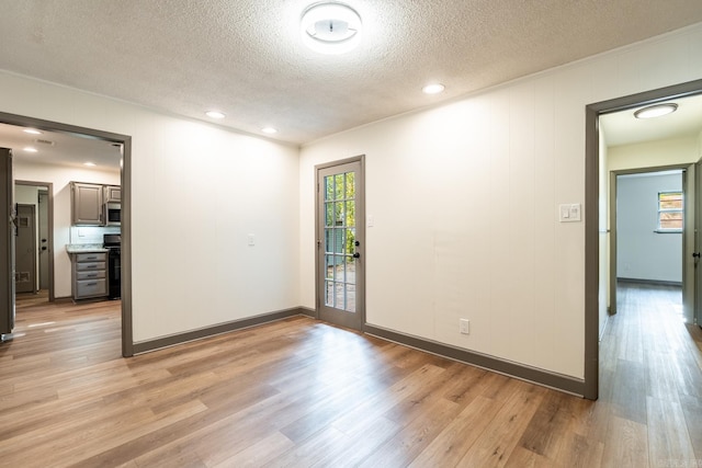 unfurnished room featuring a textured ceiling and light hardwood / wood-style flooring