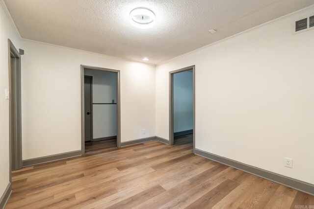 empty room featuring light wood-type flooring and a textured ceiling