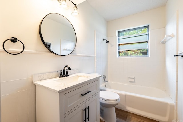 full bathroom featuring vanity, a textured ceiling, tiled shower / bath, toilet, and hardwood / wood-style flooring