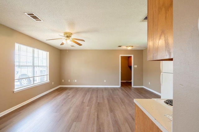 interior space featuring ceiling fan, light wood-type flooring, and a textured ceiling