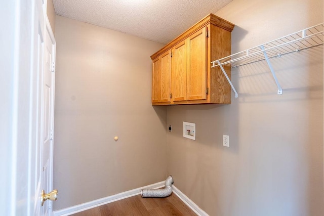 laundry area with hardwood / wood-style flooring, a textured ceiling, hookup for a washing machine, hookup for an electric dryer, and cabinets