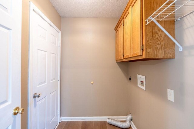 washroom featuring wood-type flooring, washer hookup, cabinets, hookup for an electric dryer, and a textured ceiling