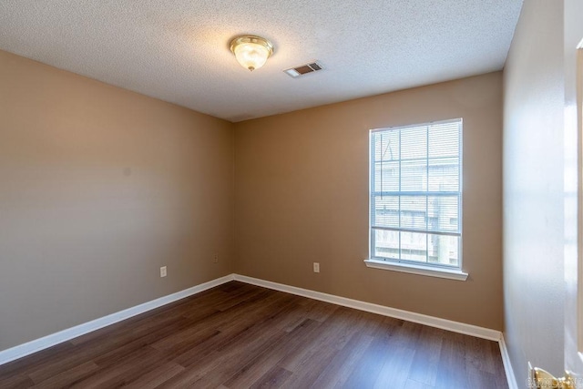 empty room with dark hardwood / wood-style flooring and a textured ceiling