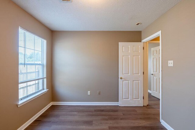 unfurnished room with a wealth of natural light, hardwood / wood-style floors, and a textured ceiling