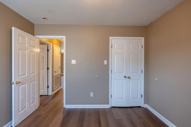 unfurnished bedroom with dark wood-type flooring and a textured ceiling