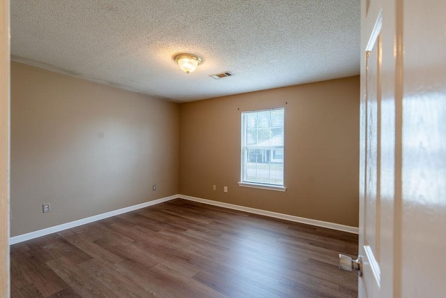 spare room featuring a textured ceiling and dark wood-type flooring