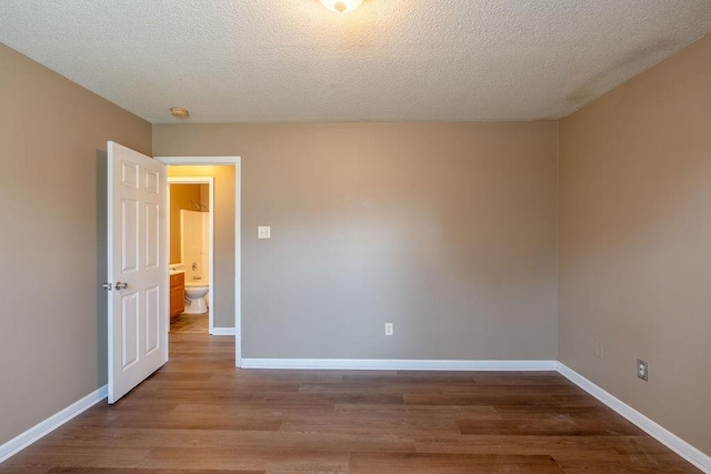 unfurnished room with a textured ceiling and wood-type flooring