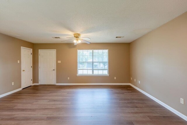 empty room with a textured ceiling, ceiling fan, and wood-type flooring