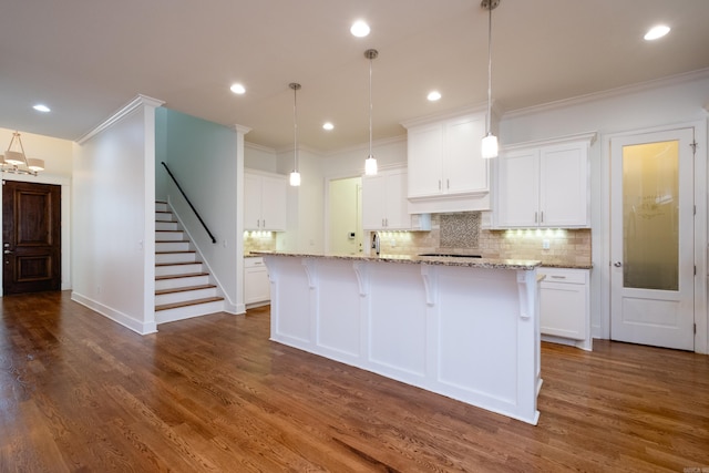 kitchen featuring backsplash, dark hardwood / wood-style floors, an island with sink, light stone countertops, and white cabinets