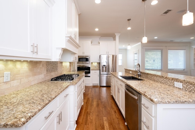 kitchen featuring backsplash, stainless steel appliances, decorative light fixtures, sink, and a kitchen island with sink