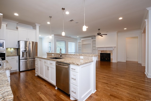 kitchen featuring stainless steel appliances, a tiled fireplace, crown molding, and hardwood / wood-style flooring