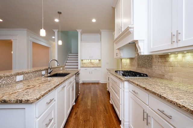 kitchen with decorative light fixtures, dark hardwood / wood-style floors, tasteful backsplash, sink, and light stone counters