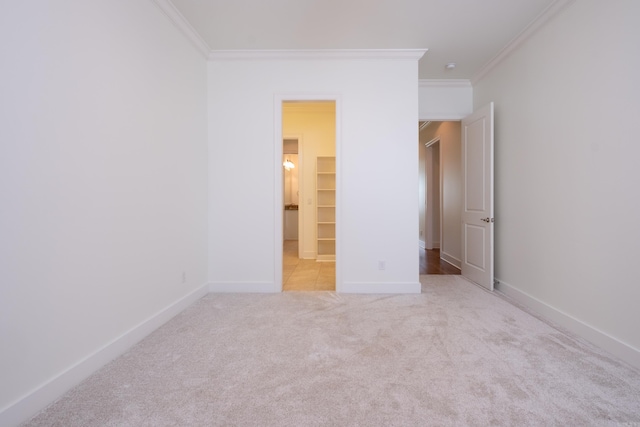 unfurnished bedroom with a walk in closet, ornamental molding, a closet, and light colored carpet