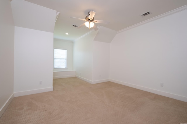 spare room featuring ceiling fan, vaulted ceiling, crown molding, and light colored carpet