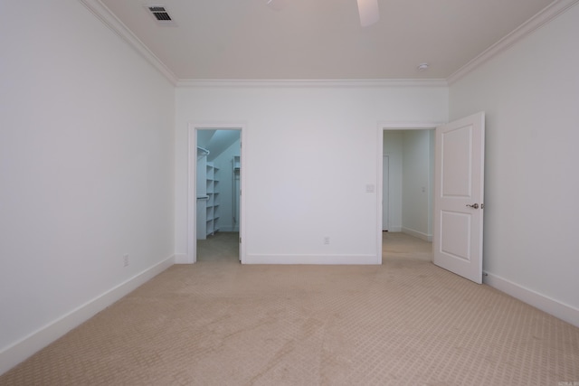 interior space featuring ceiling fan, ornamental molding, and light carpet