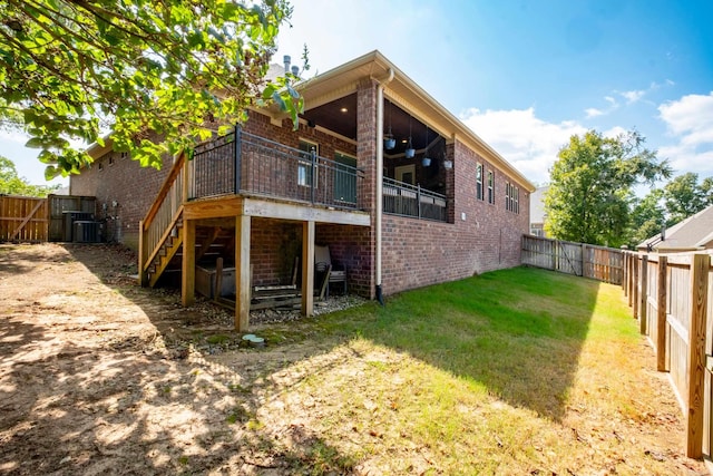 rear view of property featuring a lawn, central AC unit, and a wooden deck