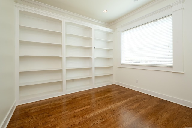 interior space with dark wood-type flooring, crown molding, and built in features