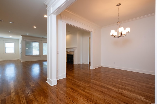 unfurnished living room with dark hardwood / wood-style floors, crown molding, and a chandelier