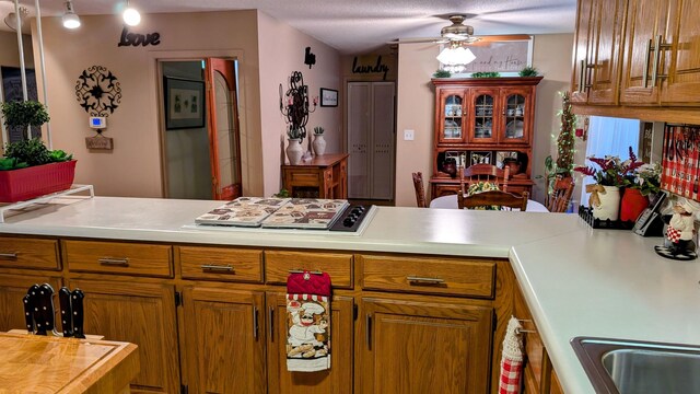 kitchen featuring ceiling fan, kitchen peninsula, a textured ceiling, and stainless steel gas cooktop