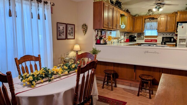 interior space with ceiling fan, light wood-type flooring, backsplash, sink, and white fridge with ice dispenser