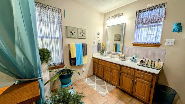 bathroom with a wealth of natural light, tile patterned flooring, a textured ceiling, and vanity