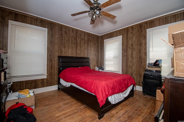 bedroom with wood walls, ceiling fan, and hardwood / wood-style flooring