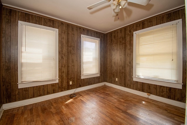 unfurnished room with ceiling fan, hardwood / wood-style flooring, and wood walls