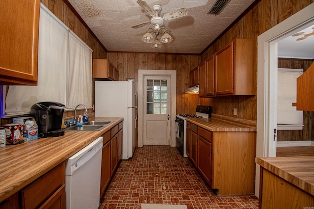 kitchen featuring wood walls, white appliances, ceiling fan, and sink