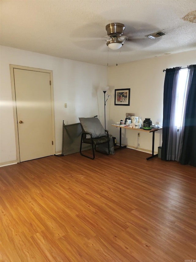 sitting room with hardwood / wood-style flooring, a textured ceiling, and ceiling fan