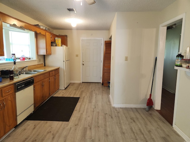 kitchen featuring sink, white appliances, a textured ceiling, and light wood-type flooring