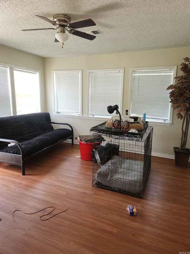 living room featuring ceiling fan, a textured ceiling, and wood-type flooring