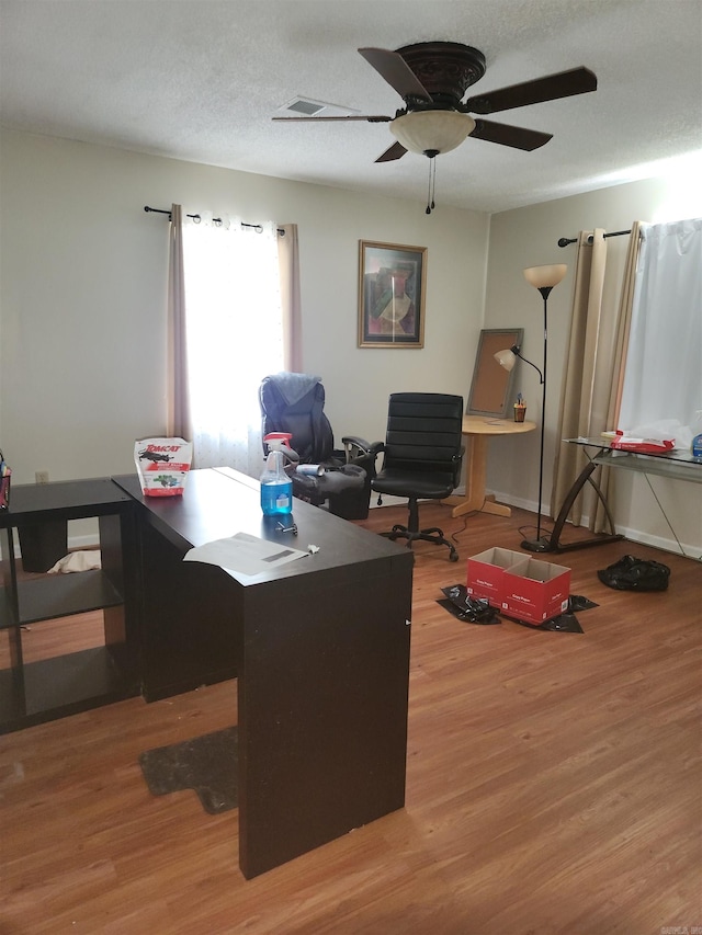 home office with a textured ceiling, ceiling fan, and hardwood / wood-style floors