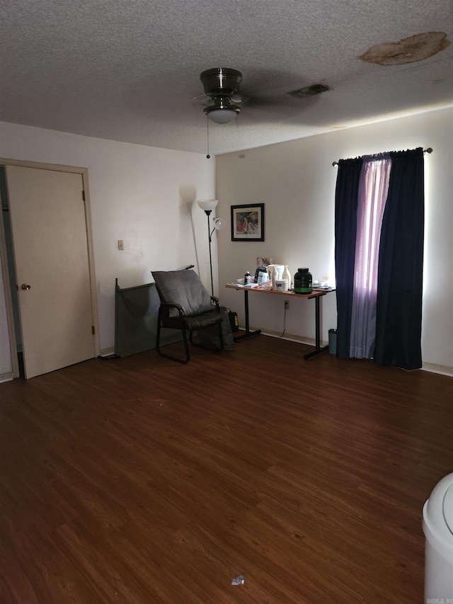 living area with hardwood / wood-style flooring, a textured ceiling, and ceiling fan