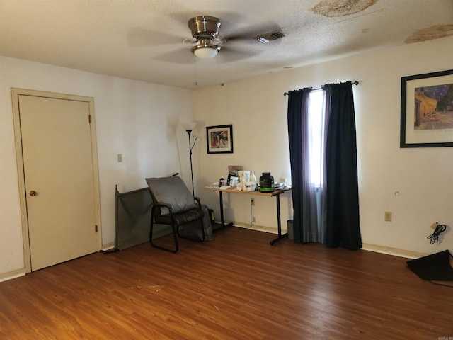 living area featuring hardwood / wood-style flooring, a textured ceiling, and ceiling fan