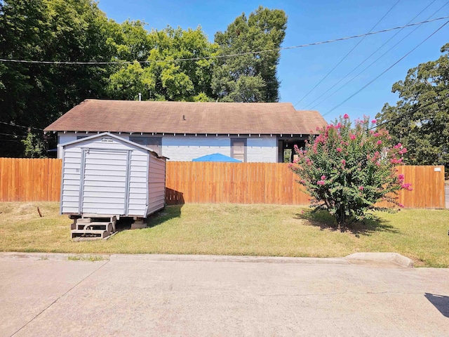 exterior space featuring a yard, a storage unit, an outdoor structure, and a fenced backyard