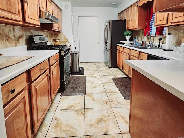 kitchen with under cabinet range hood, a sink, light countertops, appliances with stainless steel finishes, and brown cabinets