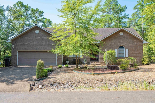 view of front facade featuring roof with shingles, aphalt driveway, and brick siding