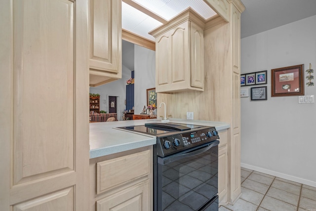 kitchen with light brown cabinetry, light tile patterned floors, light countertops, and black electric range oven