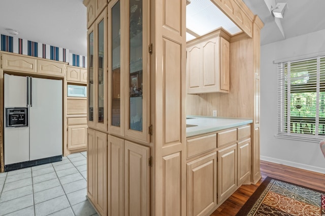 kitchen featuring light brown cabinets, white appliances, light countertops, and glass insert cabinets