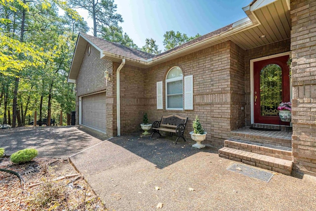 entrance to property with driveway, brick siding, and a garage