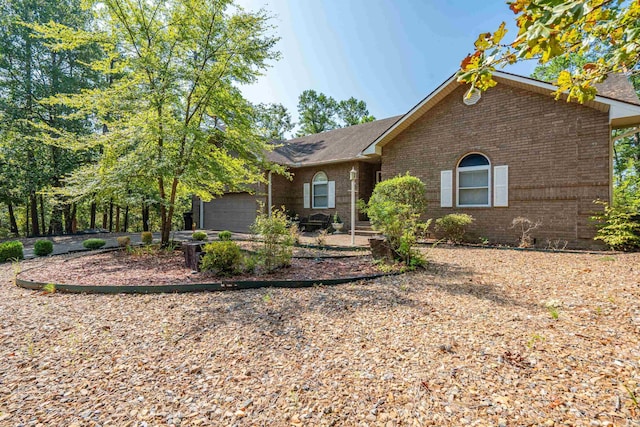 ranch-style home with an attached garage, a shingled roof, and brick siding