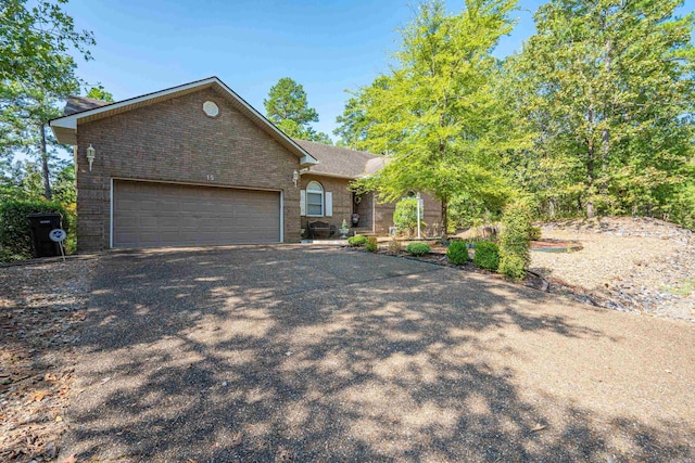 ranch-style home featuring brick siding, aphalt driveway, and an attached garage