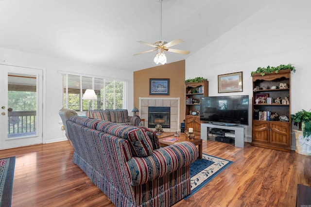 living area featuring a tile fireplace, ceiling fan, vaulted ceiling, and wood finished floors