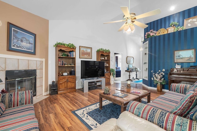 living area featuring baseboards, wood finished floors, ceiling fan, and a fireplace