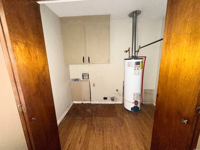 washroom featuring water heater, cabinets, hookup for a washing machine, and hardwood / wood-style floors