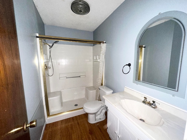 bathroom featuring hardwood / wood-style flooring, a textured ceiling, vanity, toilet, and walk in shower