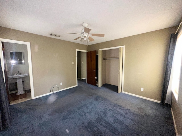 unfurnished bedroom featuring sink, a closet, connected bathroom, carpet flooring, and ceiling fan