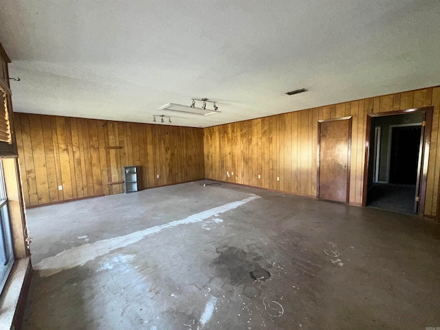 spare room with wood walls, a textured ceiling, and concrete flooring