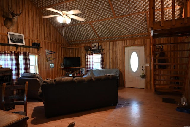 living room with high vaulted ceiling, wood walls, hardwood / wood-style floors, and a healthy amount of sunlight